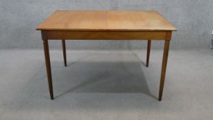 A vintage teak dining table fitted with integral fold out central leaf on circular section