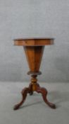 A Victorian walnut trumpet form sewing table with hinged top revealing fitted lift out interior on