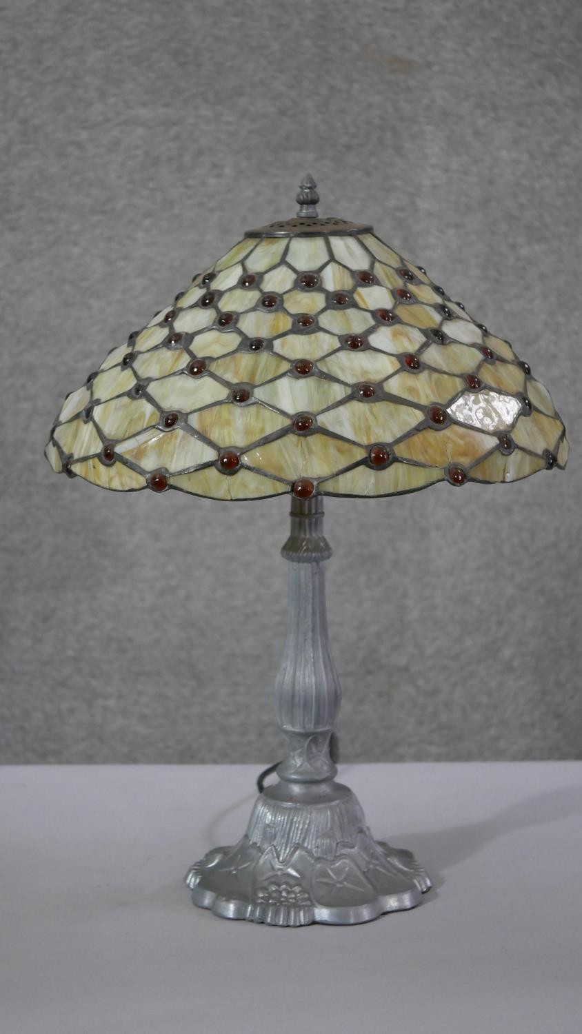 A vintage Tiffany style leaded stained glass table lamp with pewter waterlily design base. H.57