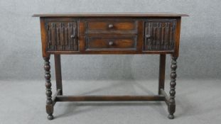 An 18th century oak sideboard with central drawers flanked by carved panel doors on bobbin turned