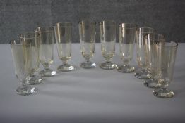 A set of ten early 20th century blown tinted glass wine glasses with circular bases. H.20