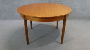 A vintage teak dining table fitted with integral fold out leaf on shaped tapering supports. H.73 W.