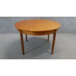 A vintage teak dining table fitted with integral fold out leaf on shaped tapering supports. H.73 W.