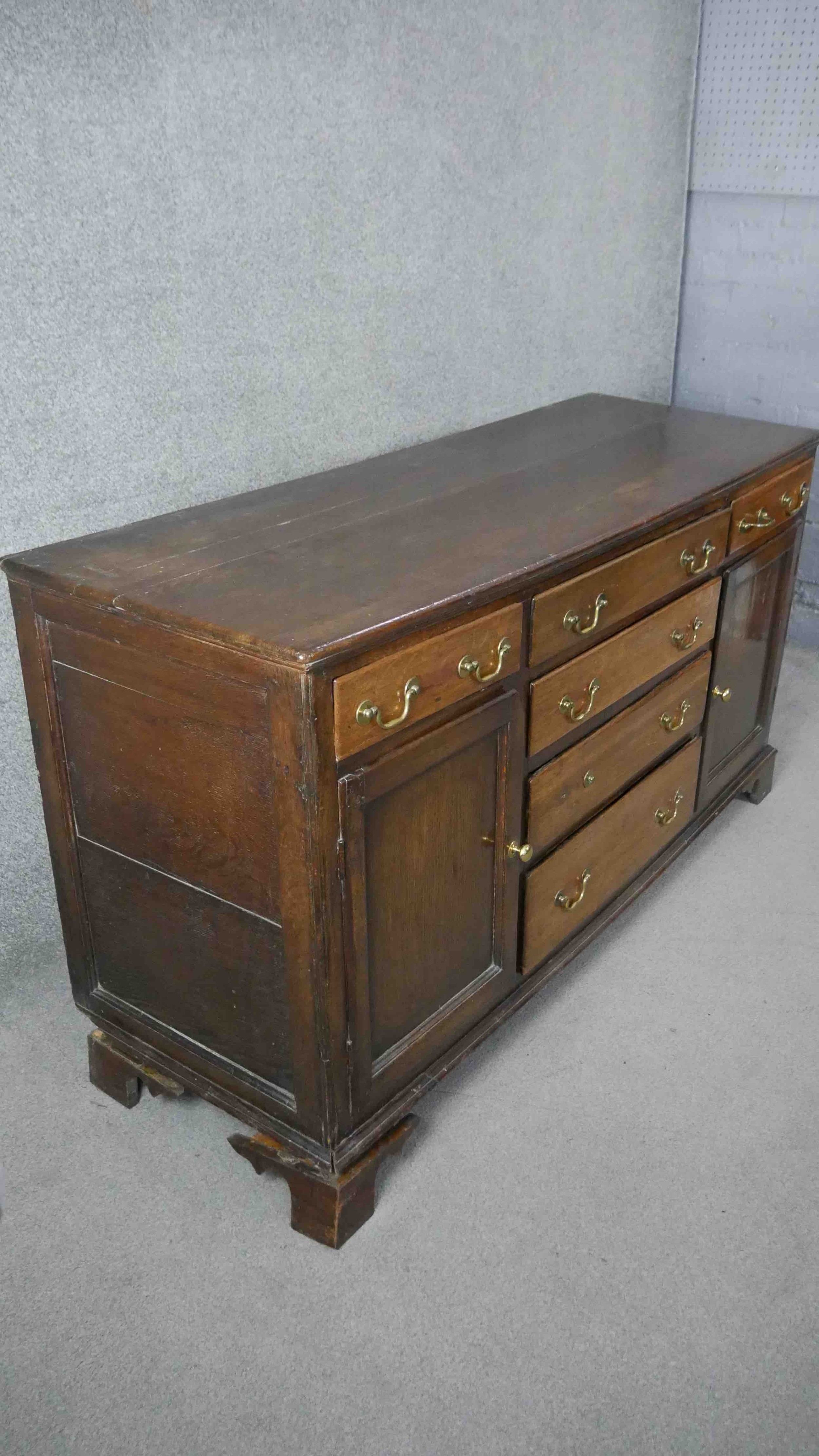 A Georgian country oak dresser base fitted with central drawers with brass swan neck handles flanked - Image 4 of 7