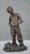 A filled bronze figure of a young boy dressing. Indistinctly signed. H.34 W.19 D.12cm