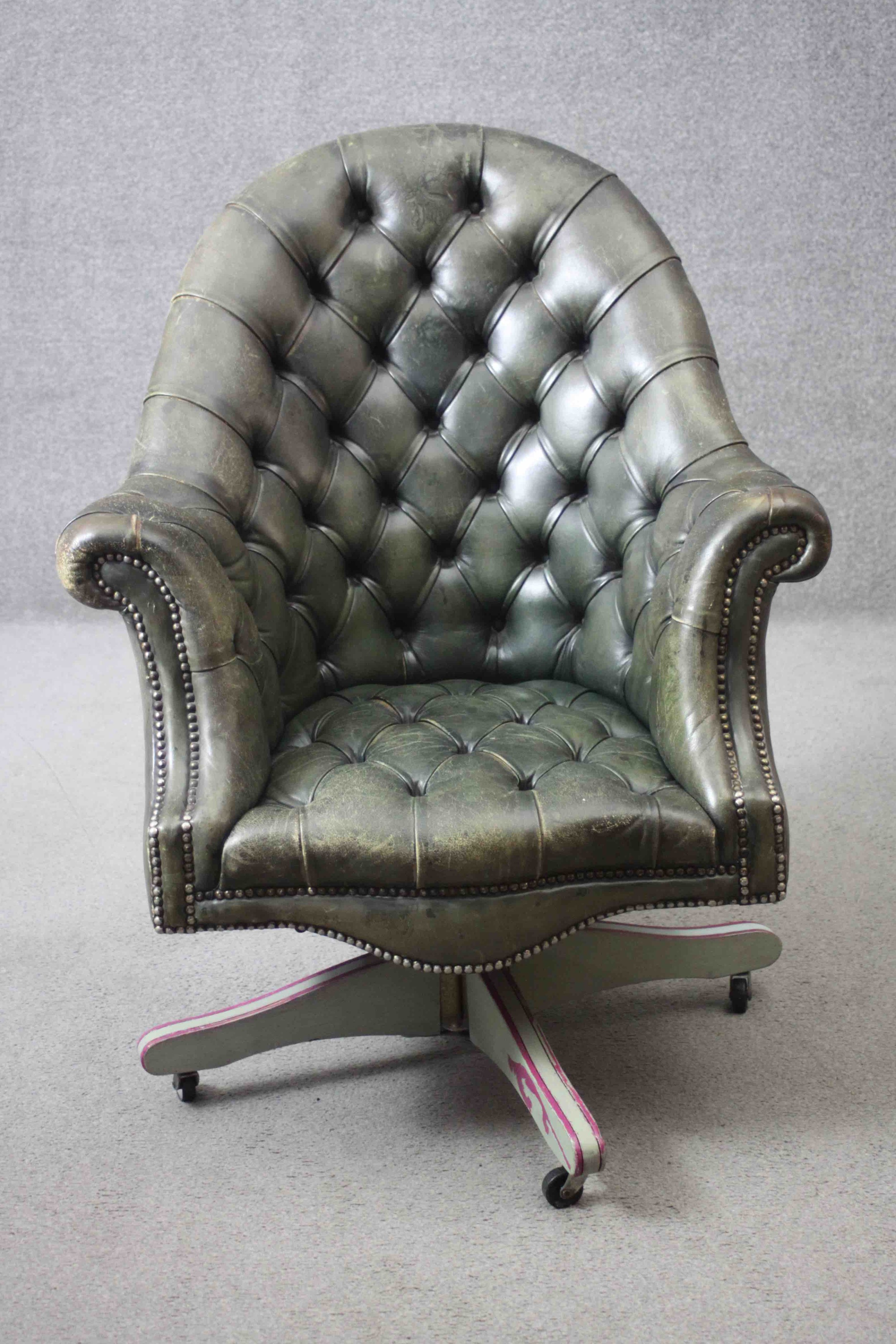 A tub shaped library armchair or desk chair in deep buttoned leather upholstery with tilt and swivel