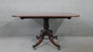 A Regency mahogany tilt top dining table on quadruped carved and swept supports terminating in brass