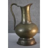 A large early 20th century engraved brass water jug with stylised floral and foliate design. H.40