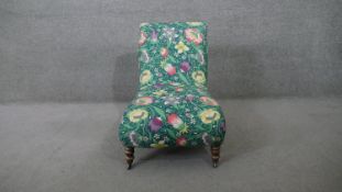 A Victorian slipper shaped nursing chair in Liberty fabric upholstery on turned tapering supports.