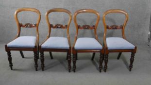 A set of four Victorian carved mahogany balloon back dining chairs with drop in seats on baluster