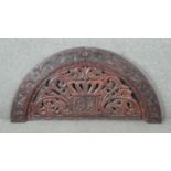 A 20th century carved and pierced Oriental semi circular panel with stylised foliate and floral