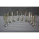 A set of ten early 20th century blown tinted glass wine glasses with circular bases. H.20