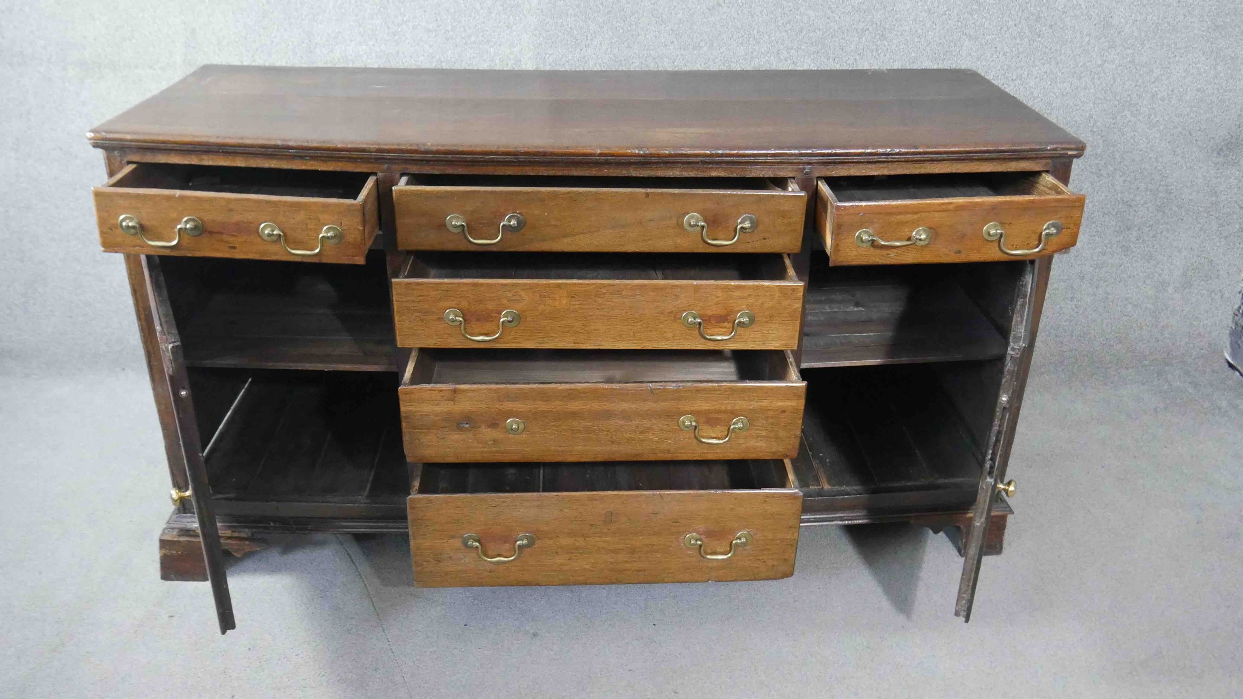 A Georgian country oak dresser base fitted with central drawers with brass swan neck handles flanked - Image 3 of 7