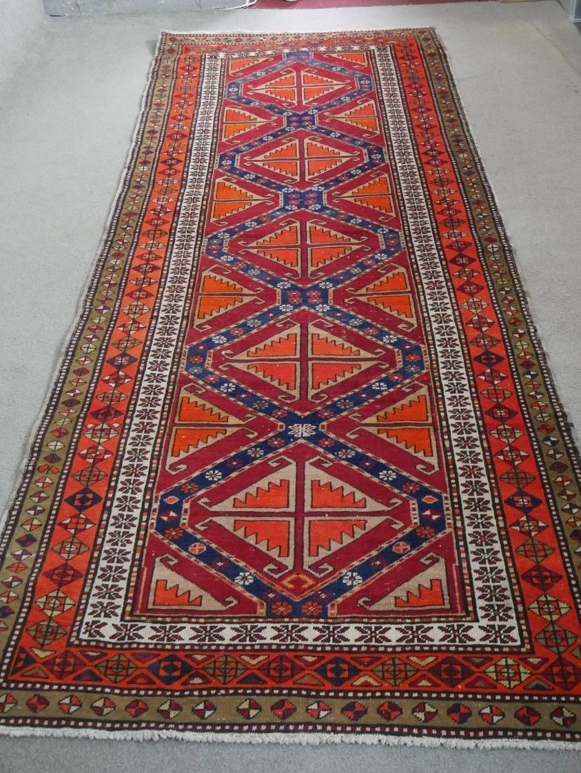 A Persian Heriz runner with repeating hooked lozenge medallions within geometric borders. L.315 W.