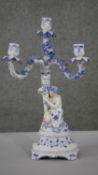 A 19th century hand painted porcelain three branch candelabra. The base modelled as a crouching