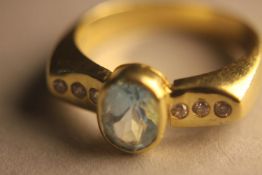 An 18 carat yellow gold, aquamarine and diamond dress ring. Set to centre with an oval mixed cut
