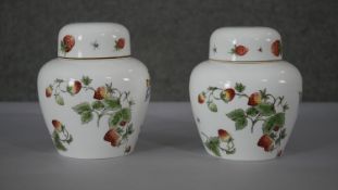 A pair of Coalport hand painted porcelain 'Strawberry' pattern lidded urns. Decorated with flowers