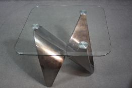 A contemporary occasional table with plate glass top on shaped brushed chromium base. H.55 W.71 D.72
