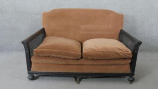 An early 20th century mahogany framed bergere sofa with carved arms on fluted bun feet. H.86 W.132
