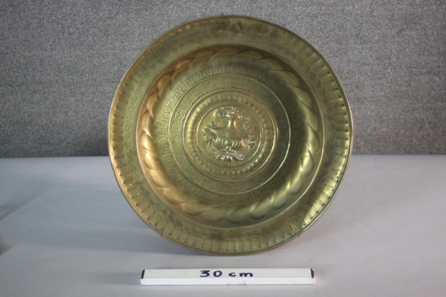 A large 19th century repousse brass charger with urn design to the centre and lettering to the edge. - Image 2 of 4