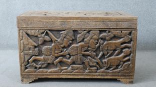 A West African carved hardwood coffer with hinged lidded top and twin locks and figural decoration.
