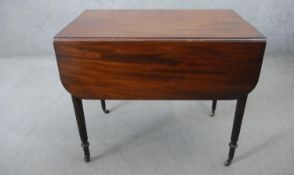A late Georgian mahogany Pembroke table on reeded tapering supports terminating in brass cap