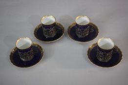 A set of four silver mounted Royal Worcester cups and saucers with gilt scrolling decoration on a