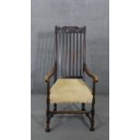 A 19th century oak Carolean style armchair with scroll cresting to the back rail and raised on