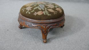 A Victorian carved walnut footstool with drop in tapestry seat. H.18 Dia.33cm