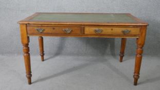 A late 19th century pitch pine writing table with inset tooled leather top on turned tapering
