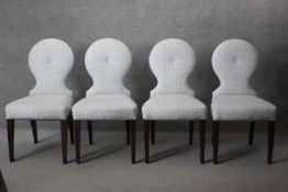 A set of four contemporary single buttoned back upholstered chairs on lacquered ebonised supports.