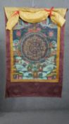 An early 20th century Tibetan hand painted Thangka with Mandala on fabric with silk brocade border