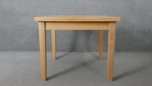 A contemporary light beech draw leaf dining table. H.74 W.90 D.166CM (extended)
