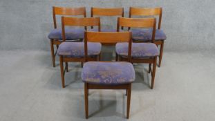 A set of six vintage teak dining chairs with floral upholstered seats on shaped tapering stretchered