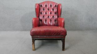 A Georgian style wingback armchair in studded and deep buttoned leather upholstery (Upholstery