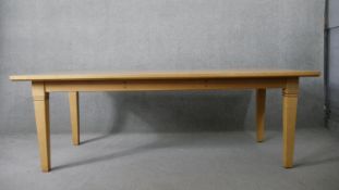 A contemporary light oak dining table on square tapering supports. H.76 W.218 D.99cm