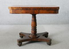 An early 19th century mahogany card table with canted fold over top on turned pedestal resting on