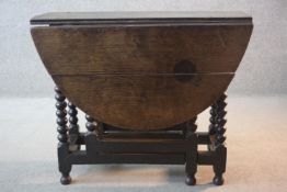 An early 18th century oak drop flap dining table on bobbin turned gateleg supports. H.73 W.120 D.