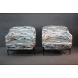 A pair of contemporary upholstered lounge armchairs on tubular metal bases.