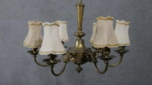 An early 20th century gilt brass six branch chandelier with cream silk shades. Swag detailing to the