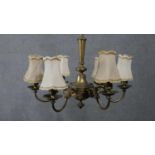 An early 20th century gilt brass six branch chandelier with cream silk shades. Swag detailing to the