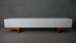 A retro styled contemporary composite laminated console cabinet on teak shaped supports. H.51 W.