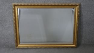 A large contemporary gilt framed mirror with repeating design bevelled plate. H.76 W.106 cm