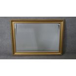 A large contemporary gilt framed mirror with repeating design bevelled plate. H.76 W.106 cm