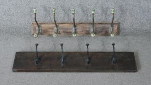 Two wall mounted coat racks. One with cast iron hooks and one with green ceramic and brass