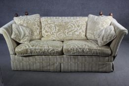 A two seater Knole sofa in cut floral brocade upholstery, drop arms with turned mahogany finials.