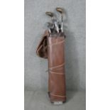 A vintage set of golf clubs. Woods, Spalding irons, and putter in a leather golf bag.