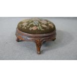 A Victorian carved walnut footstool with drop in tapestry seat. H.18 Dia.33cm