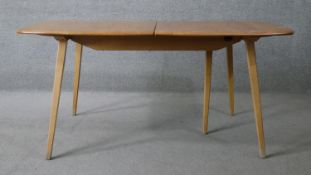 A mid century elm topped Ercol extending dining table with hinged two section leaf raised on light