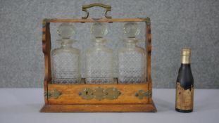 A Victorian oak and brass lockable tantalus (key missing) with three cut crystal decanters with